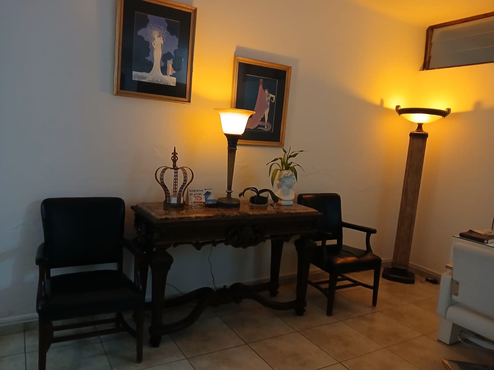 Reception area with an antique desk, warm lamps and a marble bust
