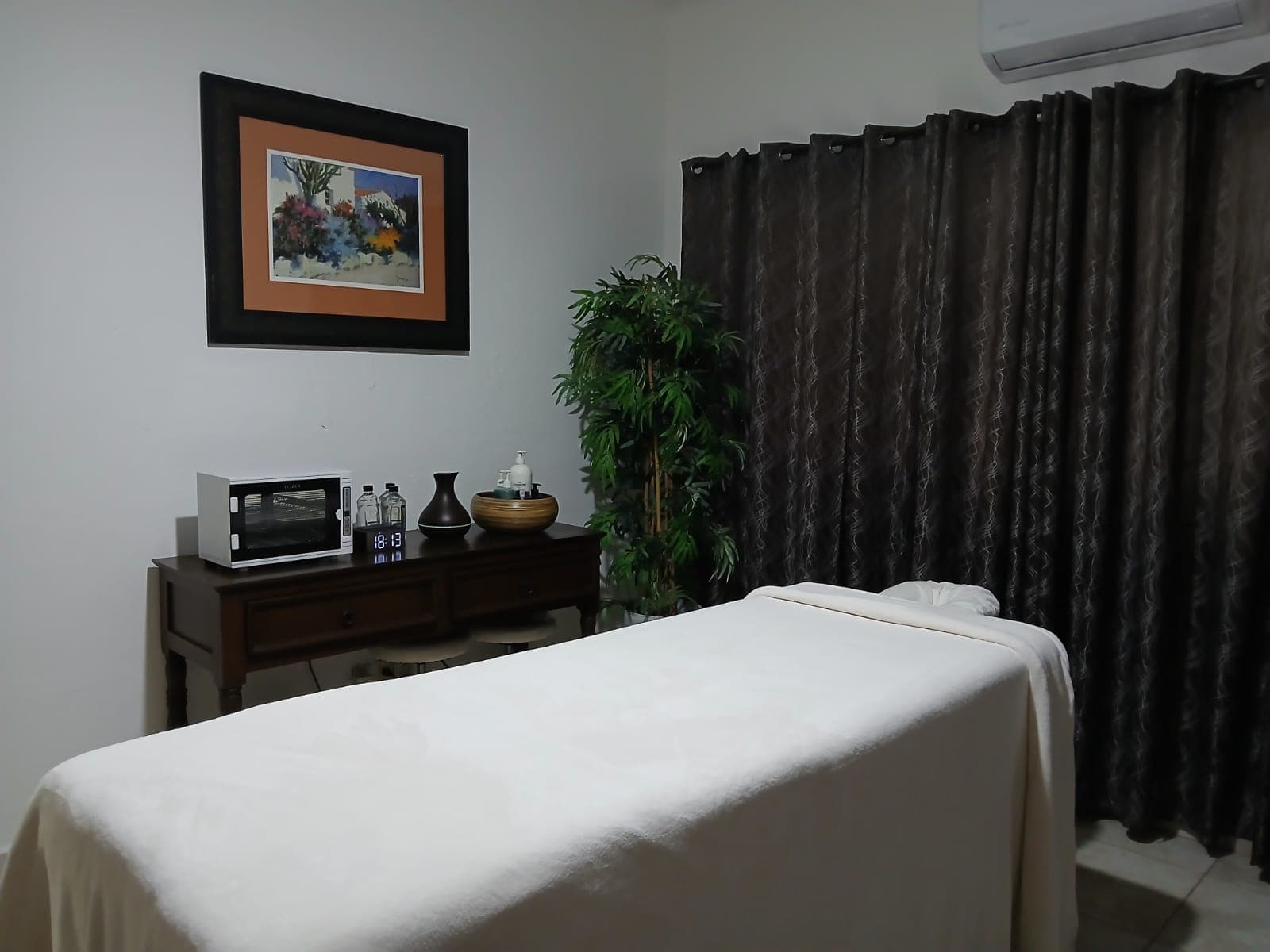 Massage room with a plant, artwork and soft curtains